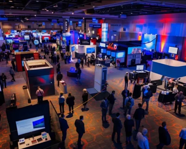 Busy exhibition floor with visitors between illuminated stands