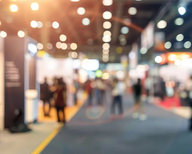 Blurred trade show aisle lined with lit exhibition booths